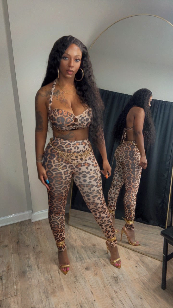 she is modeling a matching leopard-print two-piece set consisting of a halter crop top and high-waisted leggings.
