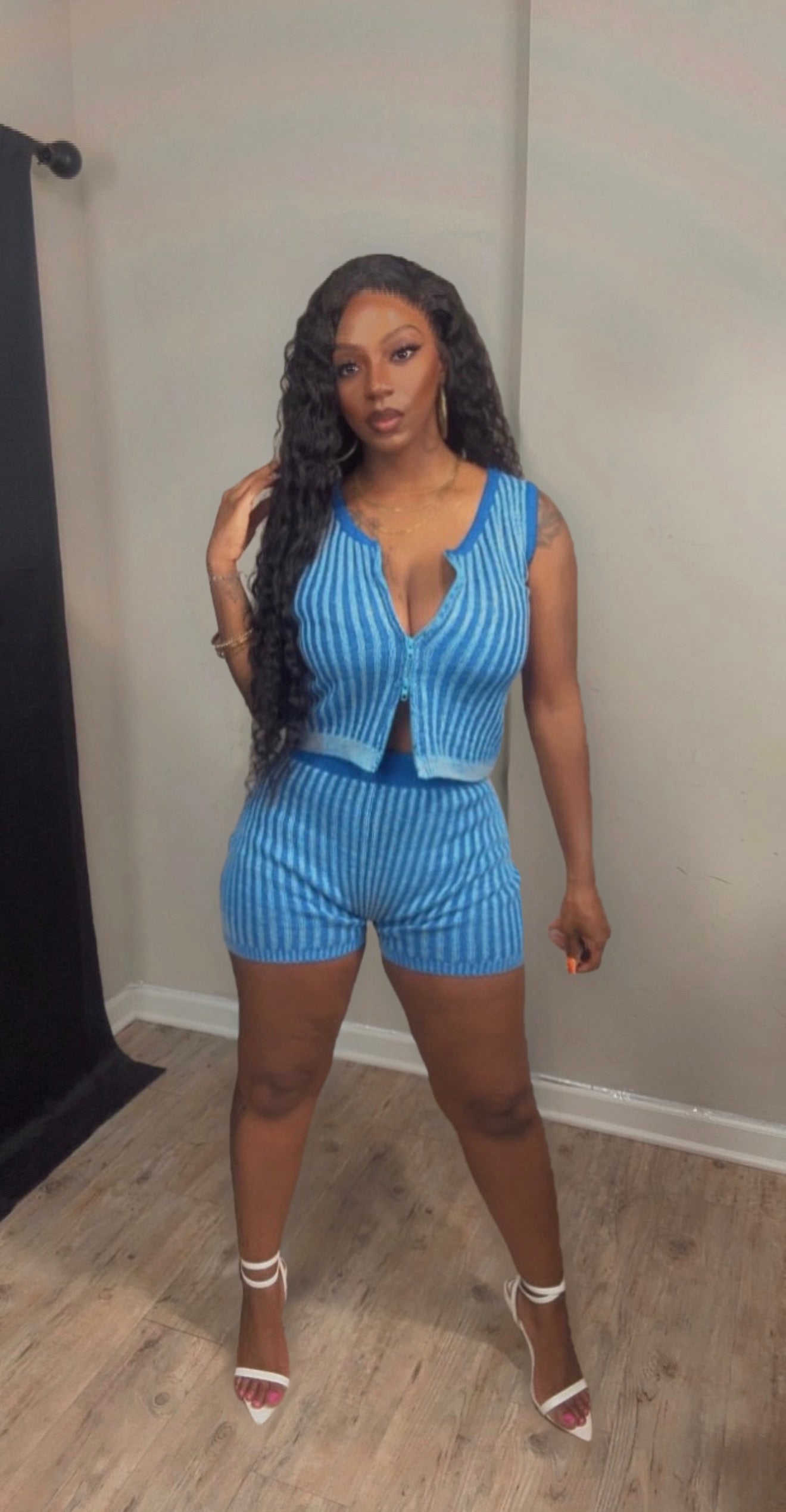 She is modeling a blue and white vertically striped two-piece set consisting of a sleeveless crop top and matching shorts.