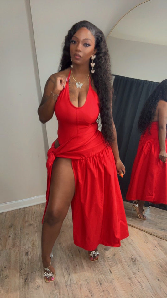 She is modeling a bright red halter-neck midi dress with a high side slit.